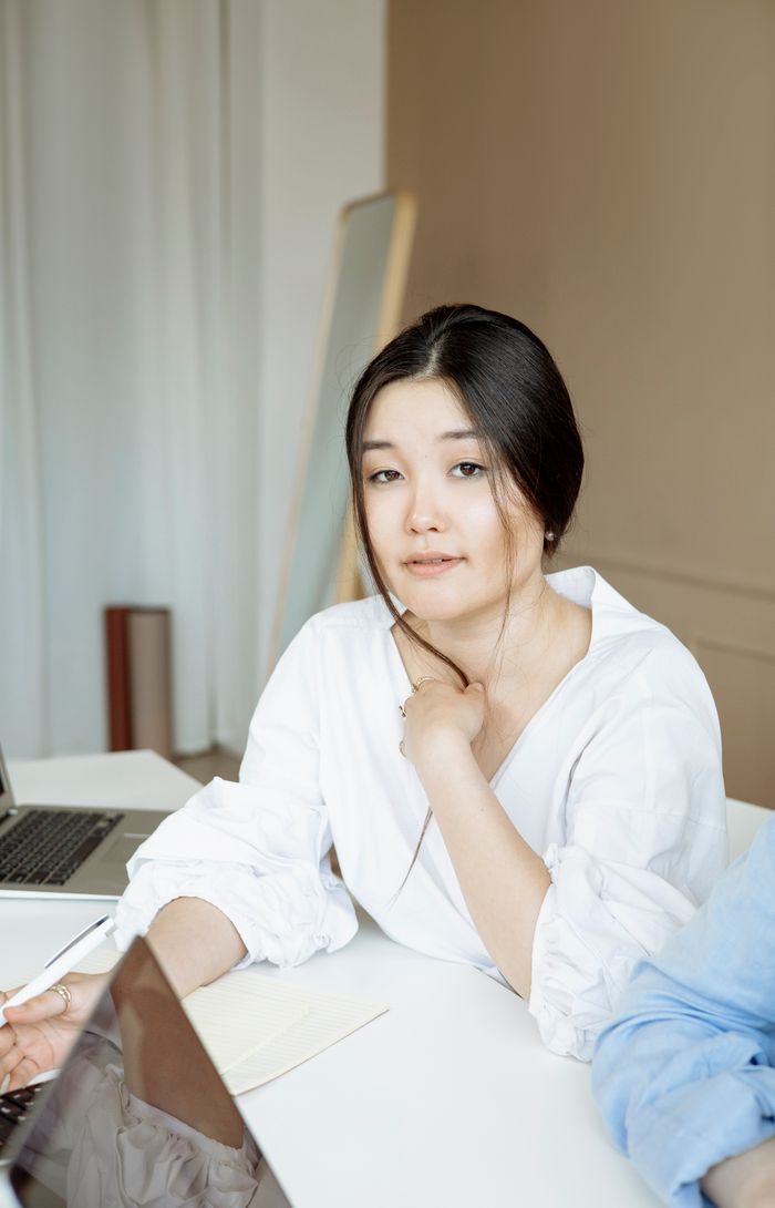 Confident woman in white blouse working at her desk in a modern office setting.